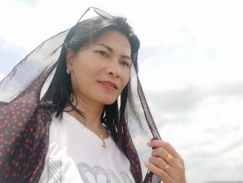 Portrait of smiling woman against sky