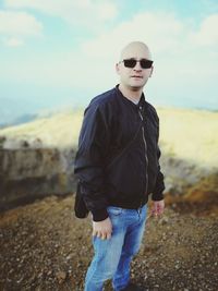 Young man standing wearing sunglasses against sky