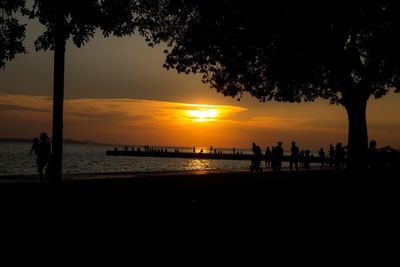 Silhouette people at beach during sunset