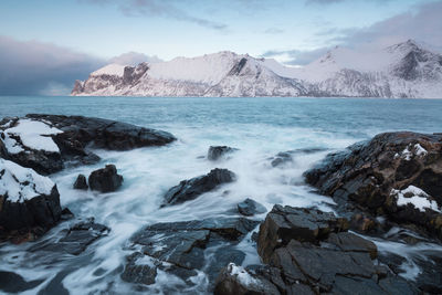 Scenic view of sea and snowcapped mountains against sky