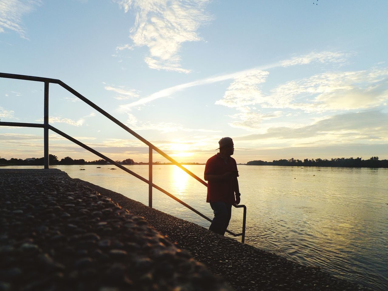 sky, water, one person, real people, sunset, railing, beauty in nature, nature, standing, lifestyles, leisure activity, full length, sea, silhouette, cloud - sky, scenics - nature, sunlight, men, outdoors