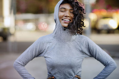 Smiling woman with hands on hips standing on street