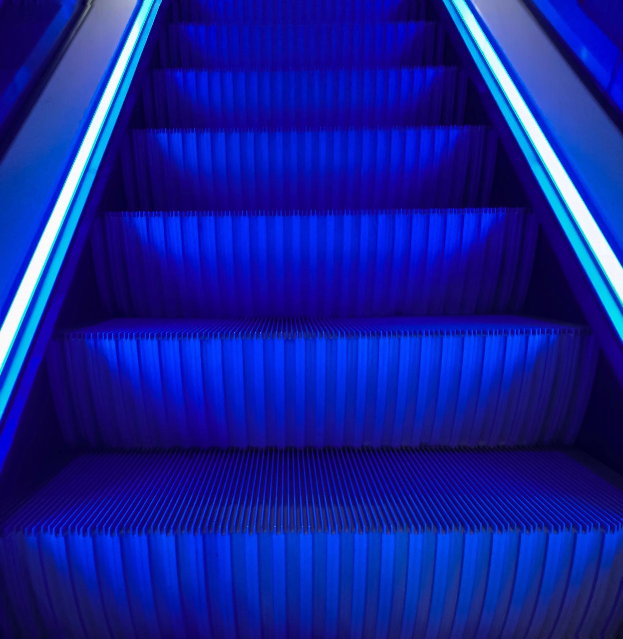 HIGH ANGLE VIEW OF ESCALATOR IN BLUE STAIRCASE