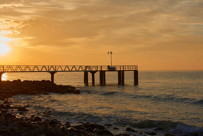 Bridge over sea against sky during sunset