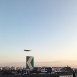 Airplane flying over city against sky