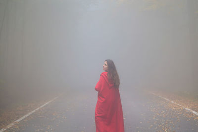 Woman standing on road in foggy weather