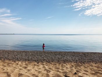 Man standing on beach against blue sky