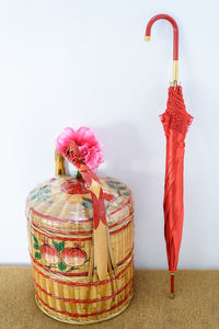 Close-up of basket and umbrella on table against white background