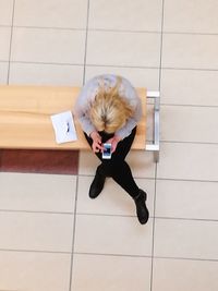 Full length of man sitting on tiled floor