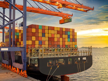 Commercial dock by sea against sky during sunset