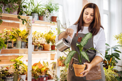 Portrait of young woman holding potted plants