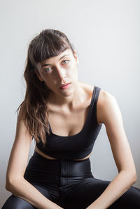 Portrait of young woman sitting against wall