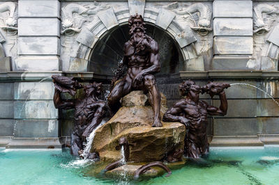 Statue by fountain against building