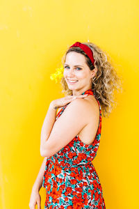 Portrait of a smiling young woman against yellow background