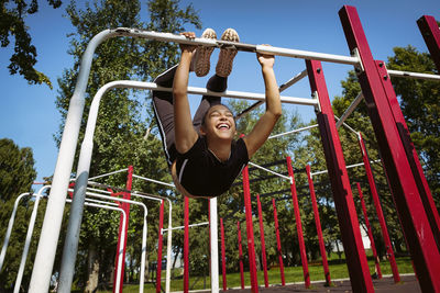 Girl in sportswear on a sunny summer day on the embankment in the park doing fitness and stretching