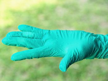 Close-up of human hand wearing rubber glove outdoors