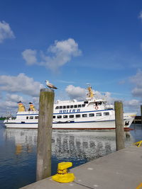 Boats moored at harbor against blue sky