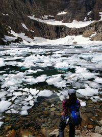Rear view of woman standing by frozen lake during winter