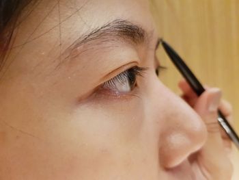 Close-up of young woman applying eyeliner