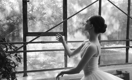 Ballet dancer standing by glass window