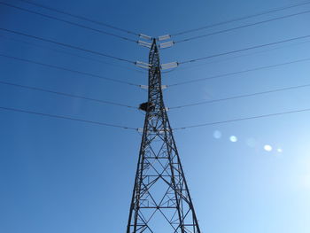 Low angle view of electricity pylon against clear blue sky