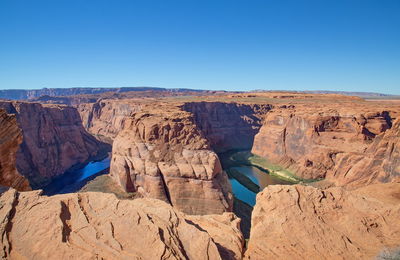 Panoramic view of rock formations against clear blue sky