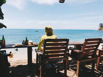 Rear view of people sitting on chair at beach