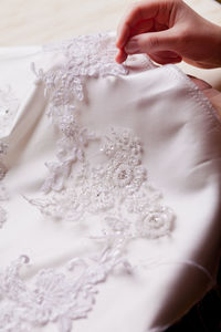 Close-up of hand sewing lace on wedding dress