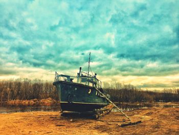 Abandoned boat moored on beach against sky