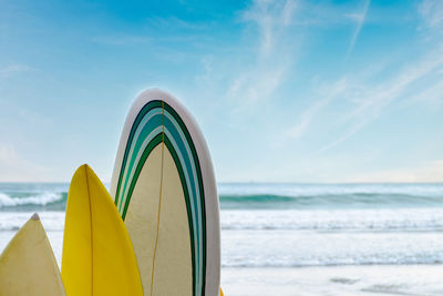 Surfboards stand in a row against the waves and blue sky, concept of leisure, sports lifestyle,