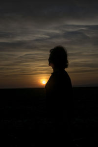 Silhouette woman standing on beach against sky during sunset