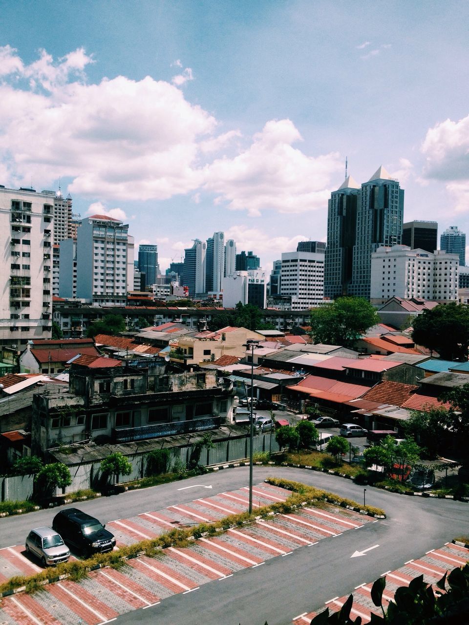 building exterior, city, architecture, built structure, cityscape, sky, street, car, skyscraper, city life, road, transportation, cloud - sky, high angle view, residential district, residential building, office building, land vehicle, city street, tower