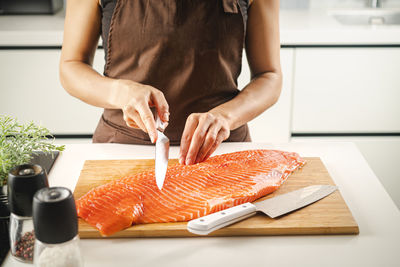 Midsection of woman preparing food on cutting board