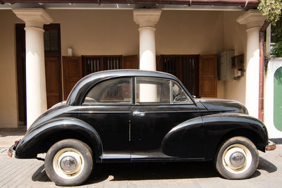 Vintage car parked on street against building during sunny day