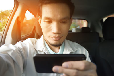Close-up of man using phone while sitting in car