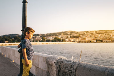 Side view of boy looking at sea against sky