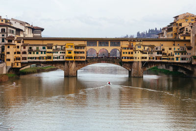 Arch bridge over river in city against sky