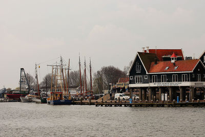 Sailboats moored at harbor by house against sky