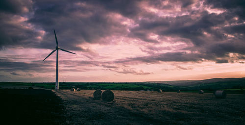 Windmills on field against sky during sunset