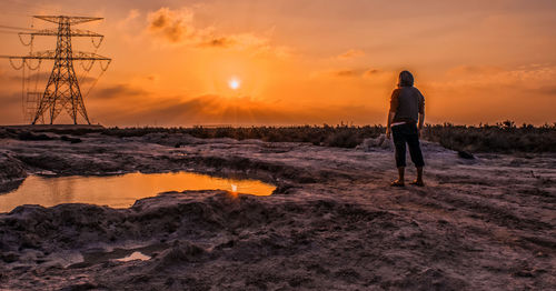 Full length of man with arms raised against sky during sunset