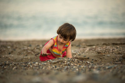 Adorable toddler baby playing on a beach with pebble stones.