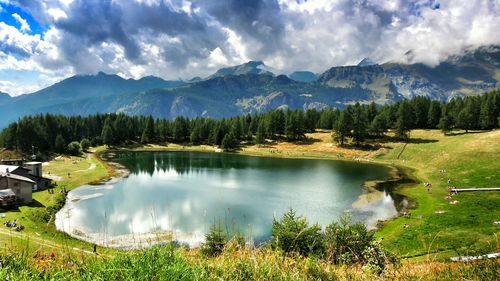 Scenic view of lake and mountains against cloudy sky