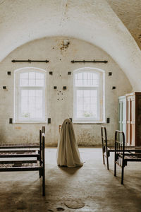 Little ghost standing in the abandoned house. autumn halloween