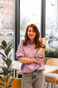 Portrait of businesswoman smiling and standing in the cafe with her arms crossed during the day.