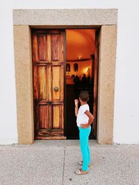 Rear view of woman standing by door of building