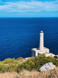 Lighthouse by sea against sky