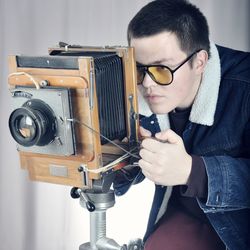 Young man photographing with vintage camera in studio