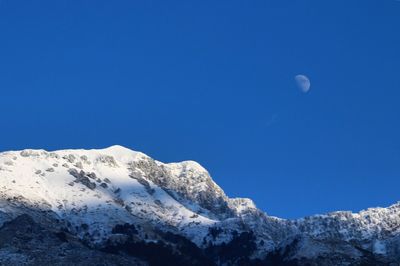 Low angle view of moon against clear blue sky
