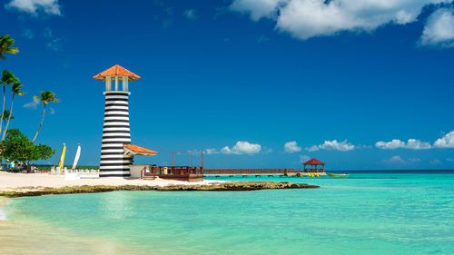 Lighthouse by sea against sky