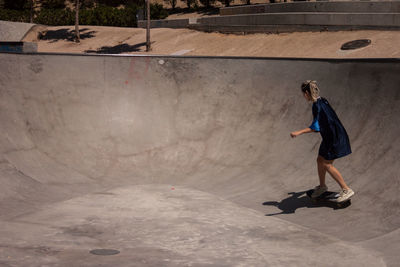 Full length of woman skateboarding at skateboard park